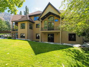 Rear view of property with a balcony, a lawn, stucco siding, a patio, and a mountain view
