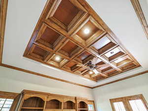 Detailed view of crown molding, coffered ceiling, beamed ceiling, and ceiling fan
