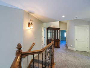 Hall with carpet flooring, an upstairs landing, and recessed lighting