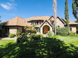English style home featuring a front yard, stucco siding, and roof with shingles