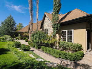 Rear view of property with stucco siding, stone siding, and a shingled roof