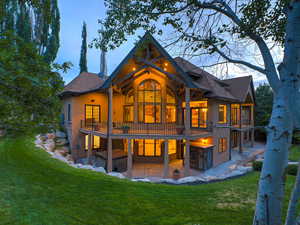 Back of property with a patio area, stucco siding, a lawn, and a balcony