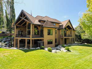 Rear view of property with a lawn, roof with shingles, stucco siding, and a patio