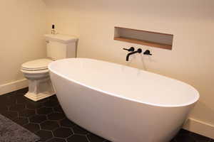 Bathroom featuring a soaking tub and dark tile patterned floors
