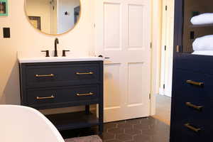 Bathroom featuring a freestanding bath, dark tile patterned floors, and vanity