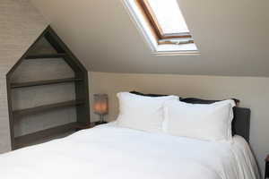 Bedroom featuring a skylight and vaulted ceiling