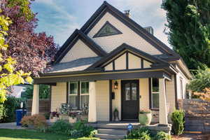 View of front facade with a porch, a chimney, and roof with shingles