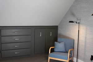 Living area with dark colored carpet and lofted ceiling
