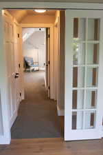 Hallway featuring dark carpet and lofted ceiling