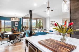 Kitchen with vaulted ceiling, decorative light fixtures, light wood-style flooring, recessed lighting, and ceiling fan