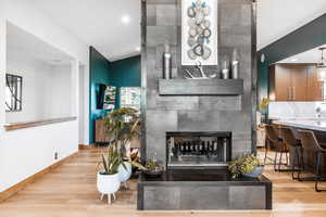 Living room with a tile fireplace, light wood-style flooring, and recessed lighting