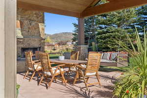 View of patio / terrace with an outdoor stone fireplace, outdoor dining area, and a mountain view