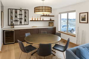 Dining space with wine cooler, light wood-style floors, and a dry bar