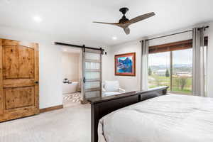 Carpeted bedroom featuring a barn door, a mountain view, ceiling fan, connected bathroom, and recessed lighting