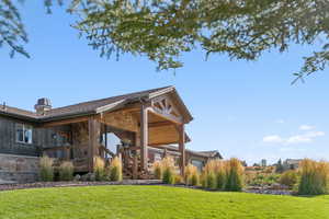 Back of property featuring stone siding, a lawn, a deck, and a chimney