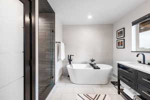 Bathroom featuring tile walls, vanity, a freestanding tub, light tile patterned flooring, and a shower stall
