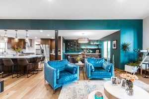 Living area with light wood-style flooring, beverage cooler, and recessed lighting