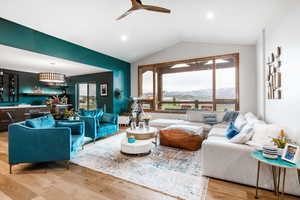 Living room featuring lofted ceiling, light wood-style floors, a mountain view, and a ceiling fan