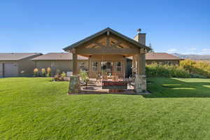 Back of house with a patio, a chimney, a lawn, and a mountain view