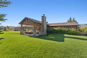 Rear view of house with a lawn, a patio area, a chimney, and stucco siding