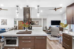 Kitchen with a ceiling fan, open floor plan, a breakfast bar, modern cabinets, and recessed lighting