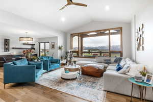 Living room featuring plenty of natural light, vaulted ceiling, light wood-style floors, and a mountain view