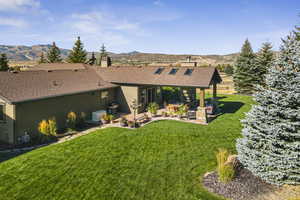View of front of house featuring a patio area, stucco siding, a front lawn, a chimney, and a shingled roof