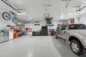 Garage with stainless steel fridge with ice dispenser and a garage door opener