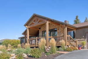 Rear view of property with stone siding, a deck, and a garage