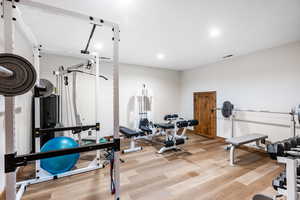 Workout area featuring light wood-type flooring and recessed lighting