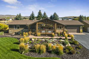 View of front of property featuring stone siding, driveway, an attached garage, and roof with shingles