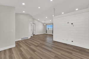 Unfurnished living room with recessed lighting, light wood-style flooring, lofted ceiling, and a chandelier