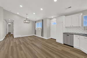 Kitchen with white cabinetry, decorative backsplash, dishwasher, dark stone counters, and recessed lighting