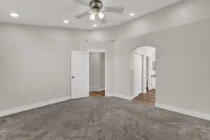 Carpeted spare room featuring arched walkways, recessed lighting, and a ceiling fan