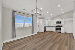 Kitchen with white cabinetry, recessed lighting, lofted ceiling, stainless steel appliances, and dark wood-style flooring
