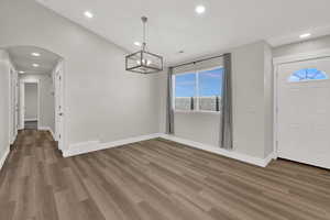 Entrance foyer with recessed lighting, wood finished floors, arched walkways, and a chandelier