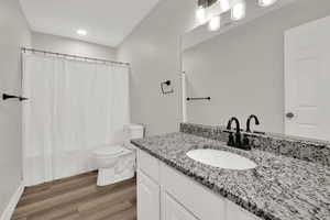 Full bathroom featuring vanity, dark wood-style floors, and recessed lighting