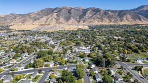 Aerial view of property and surrounding area featuring nearby suburban area and a mountainous background