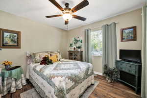 Bedroom with dark wood finished floors, a textured ceiling, and a ceiling fan