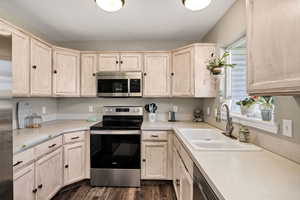 Kitchen featuring appliances with stainless steel finishes, light brown cabinets, light countertops, and dark wood-style floors