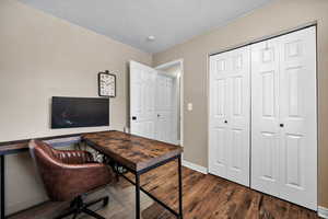 Office area with dark wood-type flooring and a textured ceiling