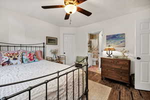 Bedroom featuring dark wood-type flooring, ceiling fan, and connected bathroom