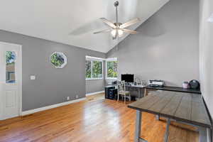 Living room with high vaulted ceiling, light wood finished floors, and ceiling fan