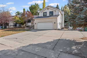 Traditional-style house featuring driveway, brick siding, a garage, and a gate