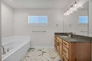 Bathroom with vanity, a garden tub, and light tile patterned flooring