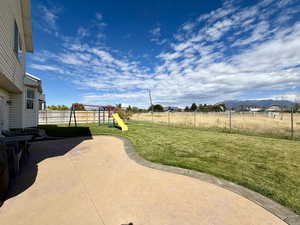 Fenced backyard with a playground, a patio area, and a mountain view