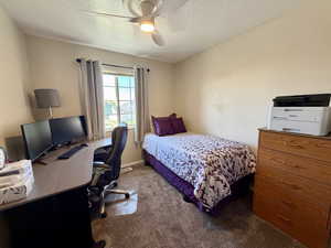 Bedroom with carpet, an office area, a ceiling fan, and a textured ceiling