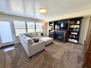Carpeted living room featuring a textured ceiling and a fireplace