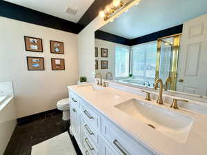 Full bathroom featuring double vanity, a bath, a stall shower, and a textured ceiling
