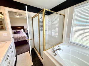 Bathroom with a garden tub, a stall shower, a textured ceiling, vanity, and ensuite bath